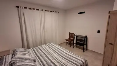 a bedroom with a bed and a chair and a window at Hermosa Casa Moderna en el Mirador del Lago in Bialet Massé