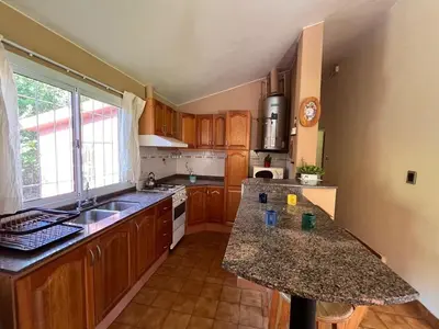 a kitchen with wooden cabinets and a granite counter top at Rocco Housse in Los Hornillos