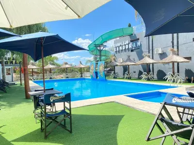 a pool with chairs and umbrellas and a water slide at Complejo Zara in Villa Carlos Paz