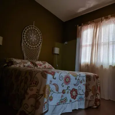 a bedroom with a bed with a flowered bedspread at Complejo Ayllu in Las Rabonas
