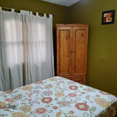 a bedroom with a bed and a wooden cabinet at Complejo Ayllu in Las Rabonas