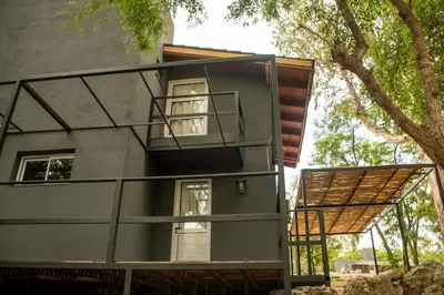 a house with a balcony and a tree at Alma Petra - Cabañas en Cabalango, Tanti, Punilla in Estancia Vieja