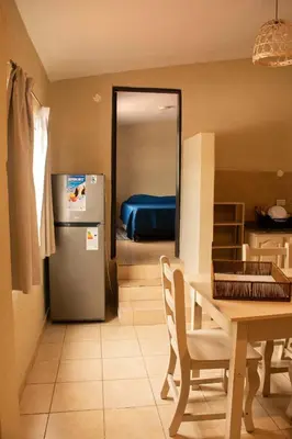a kitchen with a table and a refrigerator and a room at Alma Petra - Cabañas en Cabalango, Tanti, Punilla in Estancia Vieja