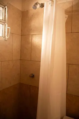 a shower with a white curtain in a bathroom at Alma Petra - Cabañas en Cabalango, Tanti, Punilla in Estancia Vieja