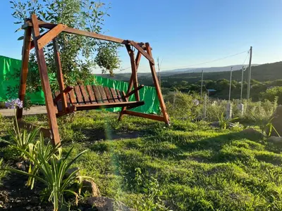 a swing in a garden with a green fence at Entre Sierras Cabañas in Tanti