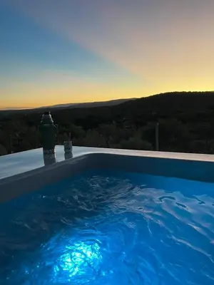a large blue swimming pool with a sunset in the background at Entre Sierras Cabañas in Tanti