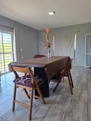 a dining room table with chairs and a vase of flowers at Entre Sierras Cabañas in Tanti