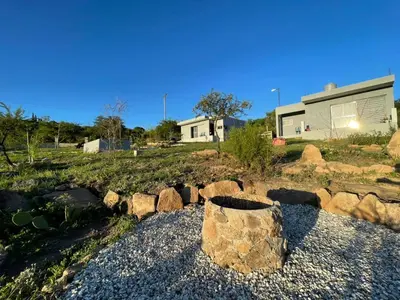a garden with rocks and a house in the background at Entre Sierras Cabañas in Tanti