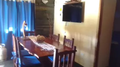 a dining room table with chairs and a television on a wall at Cabañas Ojo de Agua in Trapiche