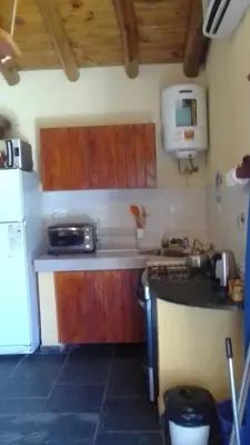a kitchen with wooden cabinets and a stove and a refrigerator at Cabañas Ojo de Agua in Trapiche