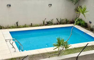 a swimming pool with plants next to a building at Departamento con piscina General Paz in Cordoba