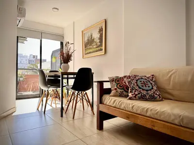 a living room with a couch and a table with chairs at Departamento con piscina General Paz in Cordoba