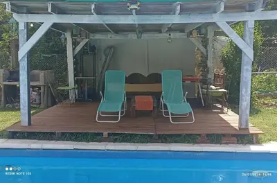 a wooden deck with a table and chairs next to a pool at Nuevos Aires in Los Reartes