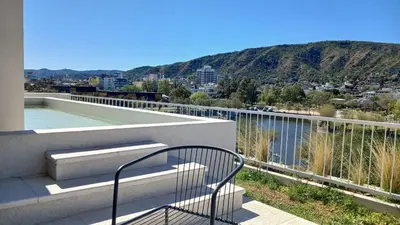 a balcony with a chair and a view of a city at ALOJATE PREMIUM VILLA CARL0S PAZ - STEFANO 1 dor in Villa Carlos Paz