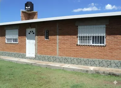a brick building with a white door and windows at Sierras y sol in Villa Cura Brochero
