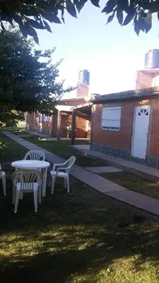 a table and chairs in the grass next to a building at Sierras y sol in Villa Cura Brochero