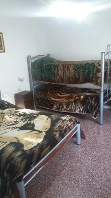 a room with three bunk beds and a bench at Sierras y sol in Villa Cura Brochero