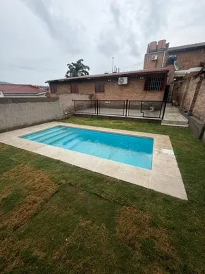 a swimming pool in a yard next to a building at Cabaña Becciu in Villa Carlos Paz