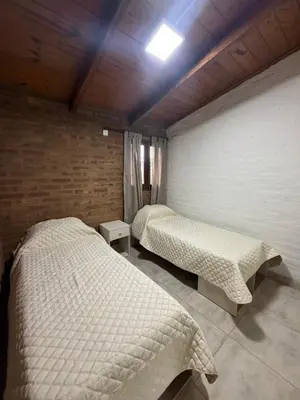 a bedroom with two beds and a wall at Cabaña Becciu in Villa Carlos Paz