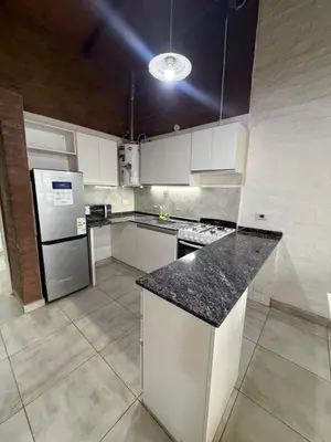 a kitchen with white cabinets and a black counter top at Cabaña Becciu in Villa Carlos Paz