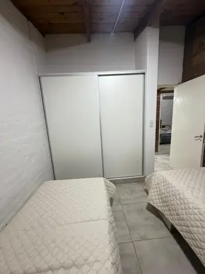 a bedroom with two beds and a sliding glass door at Cabaña Becciu in Villa Carlos Paz
