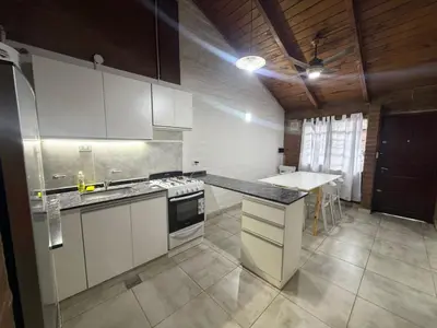 a kitchen with white cabinets and a counter top at Cabaña Becciu in Villa Carlos Paz