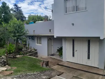 a white house with a driveway and a yard at Cactus in Villa Carlos Paz