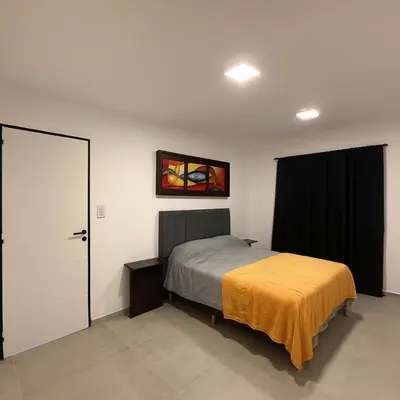a bedroom with a bed with a yellow blanket on it at Departamentos Cañitas in Malagueño