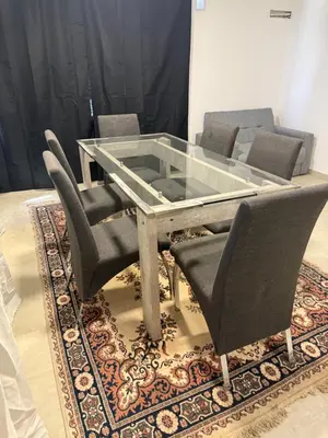 a glass dining table and chairs on a rug at Departamentos Cañitas in Malagueño