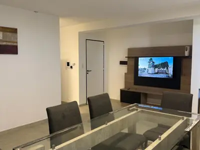 a room with a glass table with chairs and a television at Departamentos Cañitas in Malagueño