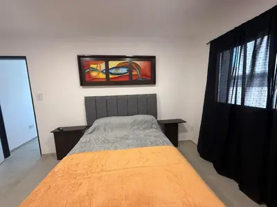 a bedroom with a bed and a painting on the wall at Departamentos Cañitas in Malagueño