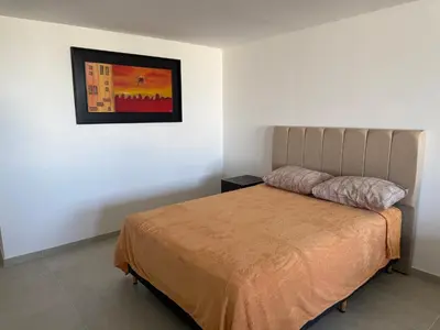 a bedroom with a bed and a painting on the wall at Monoambiente Cañitas in Malagueño
