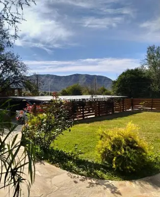 a yard with a fence and flowers in the grass at Complejo alpinas del valle in Santa Rosa de Calamuchita