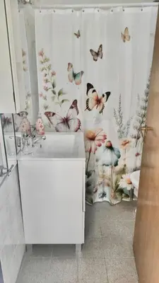 a bathroom with a sink and a shower curtain with butterflies at Departamento de lujo, todo confort, en el corazón de zona norte in Cordoba