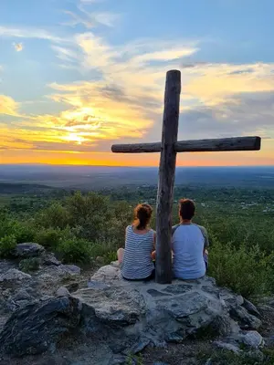 a man and a woman sitting next to a wooden cross at Cabañas Rincon del Champa in San Javier