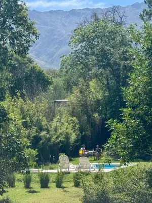 a group of people sitting around a table by a pool at Cabañas Rincon del Champa in San Javier