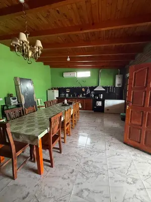 a dining room with a table and chairs and green walls at Quincho El Aguaribay in Villa Dolores