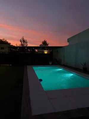 a swimming pool with a sunset in the background at Quincho El Aguaribay in Villa Dolores