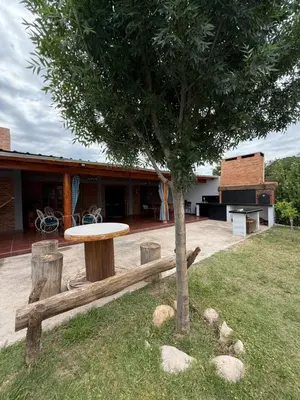 a table and a tree in a yard at Quincho El Aguaribay in Villa Dolores