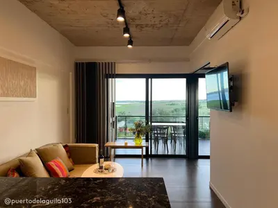 a living room with a couch and a large window at Departamento 103 - Puerto del Aguila Country Nautico in Potrero de Garay
