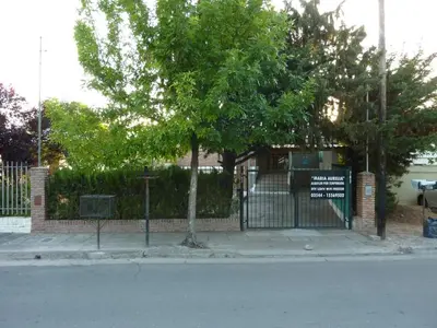 a fence with a tree in front of a building at MariaAurelia in Mina Clavero