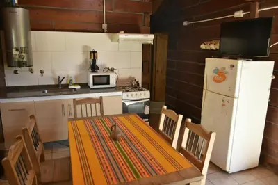 a kitchen with a table and a white refrigerator at Villa Armonia in Los Reartes