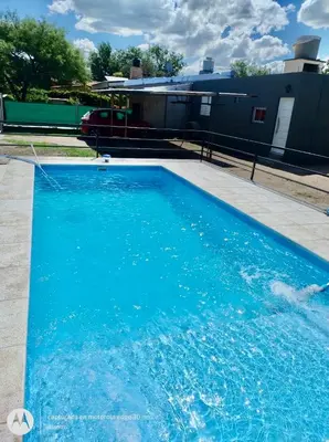 a swimming pool with blue water in front of a house at Departamentos Don Luis in Villa Cura Brochero
