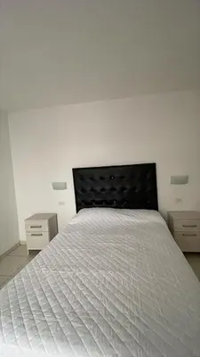 a bedroom with a white bed with two night stands at Departamento hasta 4 personas Villa Dolores in Villa Dolores