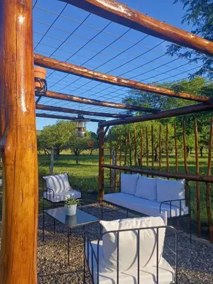 a pergola with white couches and tables on a patio at DoñaMaria in Santa Rosa de Calamuchita