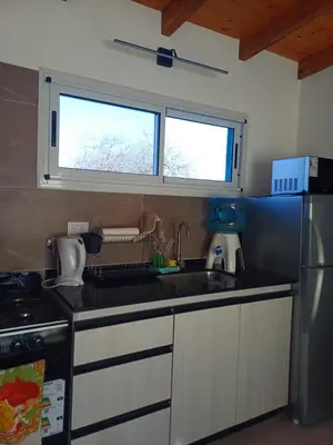 a kitchen with a sink and a stove and two windows at DoñaMaria in Santa Rosa de Calamuchita