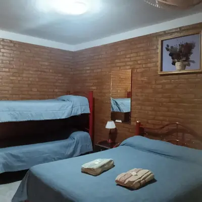 a bedroom with two beds and a mirror at Hostería HuAneL in Villa Cura Brochero