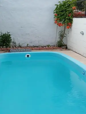a blue swimming pool in front of a house at La Casita del Tano con Pileta in Villa Carlos Paz