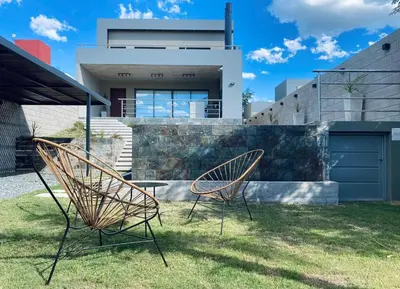 two chairs sitting in the grass in front of a house at Casa lujosa en Tanti in Tanti
