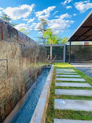 a stone retaining wall with a stream in a yard at Casa lujosa en Tanti in Tanti